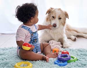 baby sitting with dog in living room
